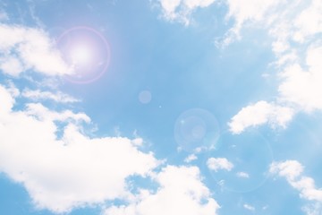Soft blue sky background with clouds. Sun glare effect