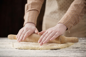  hands cooking dough on dark wooden background