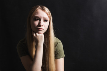 Sad young woman going to cry in a black background