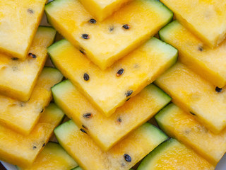 Summer background. Triangles of juice yellow watermelon, top view, macro