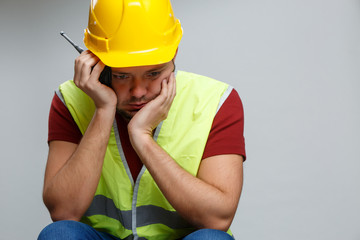 Photo of unhappy builder male in yellow helmet with walkie-talkie .