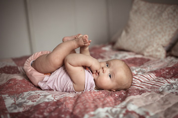 Cute cheeky baby lies on back and keeps his hands