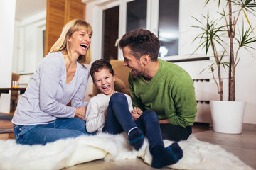 Obraz premium Happy family having fun on floor of in living room at home, laughing.