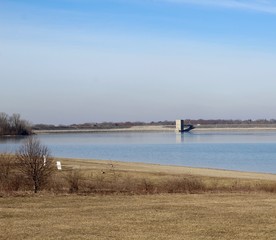 A view of the large dam and the lake on a sunny day.