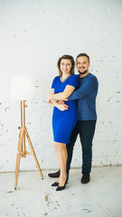 Beautiful stylish young couple at home hugging and laughing at the camera. Vertical frame. Blue dress
