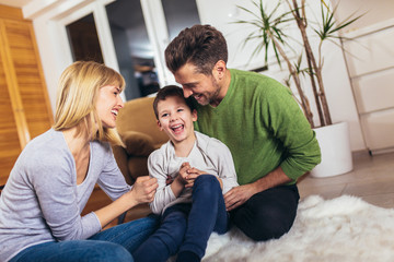 Happy family having fun on floor of in living room at home, laughing.