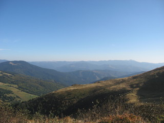 Mountain landscape with blue sky. View of the mountains and green hills from above.