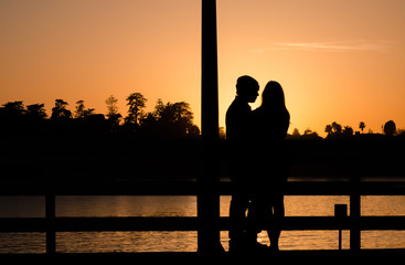 Romantic couple on a pier in Santa Cruz hugging during sunset