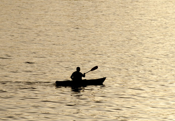 Silhouette of undefined kayaker on water at beautiful sunset time. Santa Cruz. California