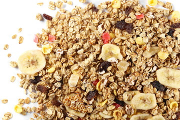 Crunchy tropical muesli pile mix with banana, pineapple, papaya slices and raisins isolated on white background