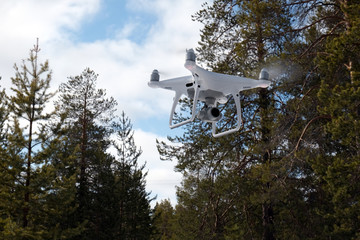 Quadcopter on the background of forest and clouds. In the background are forest, clouds and trees.