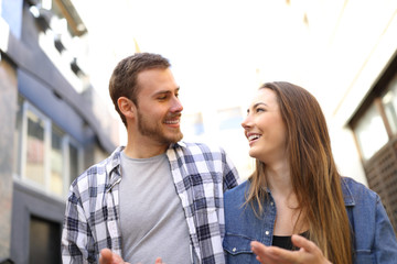Couple walking in the street talking looking each other