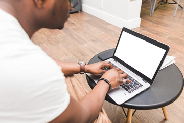 Young African American businessman remotely working at home on a laptop.