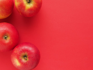Red organic apples on a red background