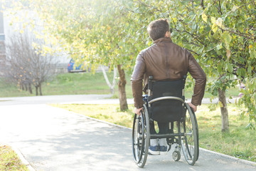 A young man in a wheelchair rides along the park road.