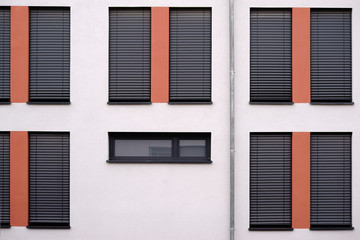 Die moderne Fassade eines modernen Wohngebäudes mit heruntergelassenen  Metalljalousien und einer Regenrinne. .