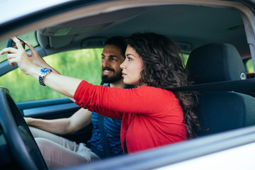 Driving school or test. Beautiful young woman learning how to drive car together with her...