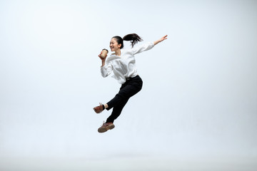 Fototapeta na wymiar Hurry up to get your coffee. Happy woman working at office, jumping and dancing in casual clothes or suit isolated on white studio background. Business, start-up, working open-space concept.