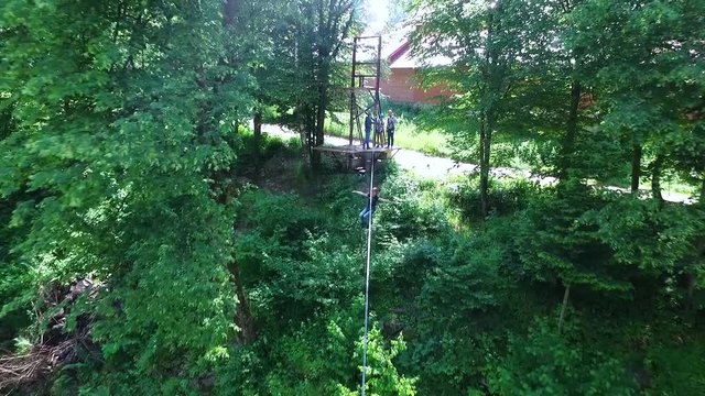 Young man on a zip line over the mountain river