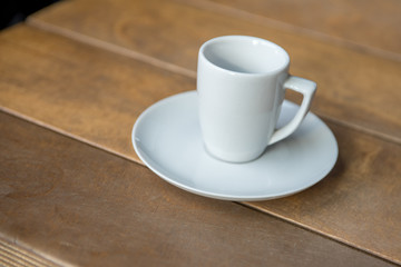 white cup with a saucer for expresso on a wooden background
