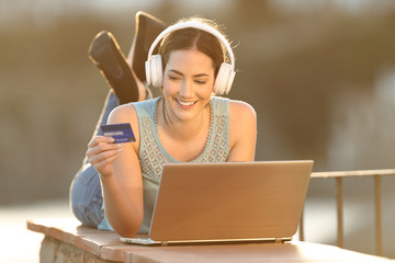Happy woman uses credit card to buy online music or media