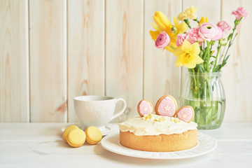 Easter cake with gingerbread on the table, the table is decorated with flowers, macaroons  and eggs