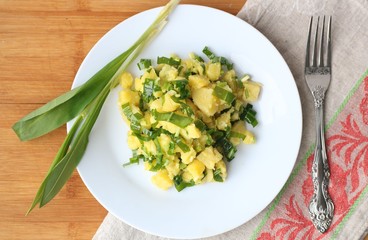 easy vitamin potato salad with Wild leek in white plate on linen and wooden table