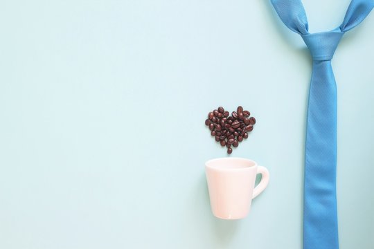 Happy Father's Day concept with blue colour necktie and coffee cup with coffee beans heart shape on pastel background