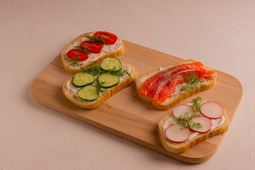 Sandwiches with salmon, cucumber, tomatoes, avocados and greens, vegetable sliced