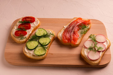 Sandwiches with salmon, cucumber, tomatoes, avocados and greens, vegetable sliced