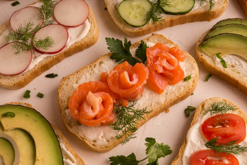 Sandwiches with salmon, cucumber, tomatoes, avocados and greens, vegetable sliced