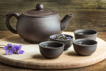 Set for tea ceremony. Large clay  teapot, fresh green tea and cups on wooden background. Front view. Copy space, space for text, isolated.
