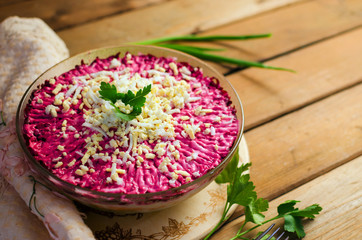 Traditional Russian herring under a fur coat on a white plate with parsley.