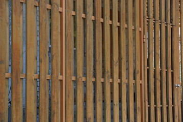 brown wooden background of thin long boards in the wall of the fence on the street