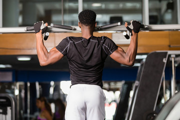 Fototapeta na wymiar Black African American young man doing pull up workout at the gym