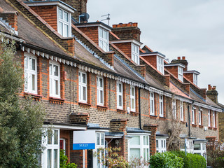 A row of typical British terraced houses with estate agent sign