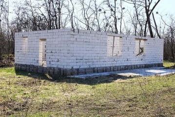 construction site with an unfinished gray brick house in green grass