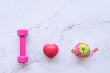 Fototapeta na wymiar I love healthy food concept, flat lay of pink dumbbell with red heart and green apple on white marble background
