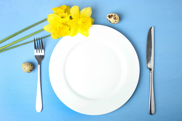 Empty plate, cutlery, quail eggs and narcissus.