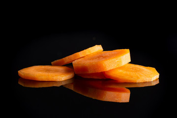 Group of five slices of fresh orange carrot isolated on black glass