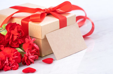 May mothers day handmade giftbox wishes photography - Beautiful blooming carnations with red ribbon bow box isolated on modern marble desk, close up, copy space, mock up
