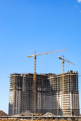 Construction of multi-storey buildings near Moscow. Construction cranes on the construction site. Sunny day.