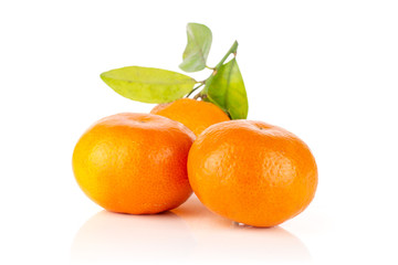 Group of three whole fresh orange mandarine with green leaves isolated on white background