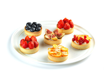 tartlets with fruits and berries in a plate on an isolated white background