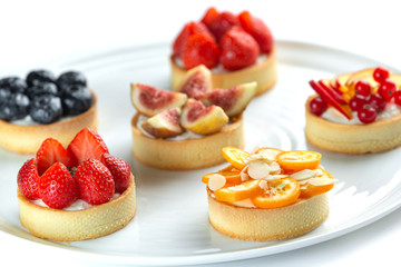 tartlets with fruits and berries in a plate on an isolated white background