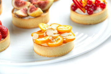 tartlets with fruits and berries in a plate on an isolated white background