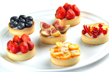tartlets with fruits and berries in a plate on an isolated white background