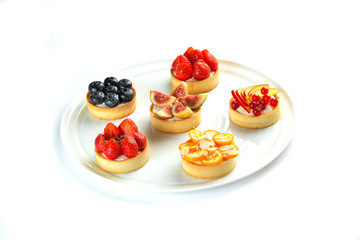 tartlets with fruits and berries in a plate on an isolated white background