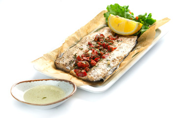 baked fish fillet with paprika; lemon and sauce on an isolated white background