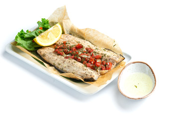 baked fish fillet with paprika; lemon and sauce on an isolated white background